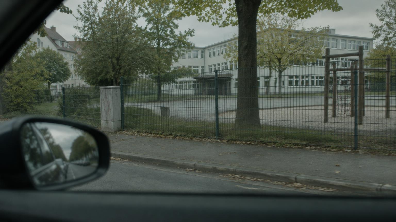 Wohnstraße und Schulhof im Tageslicht, durch ein Autofenster gesehen